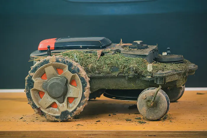 Ab zum Fachhändler in die Reinigung! Ein Mähroboter voller Gras und Dreck vor der Reinigung